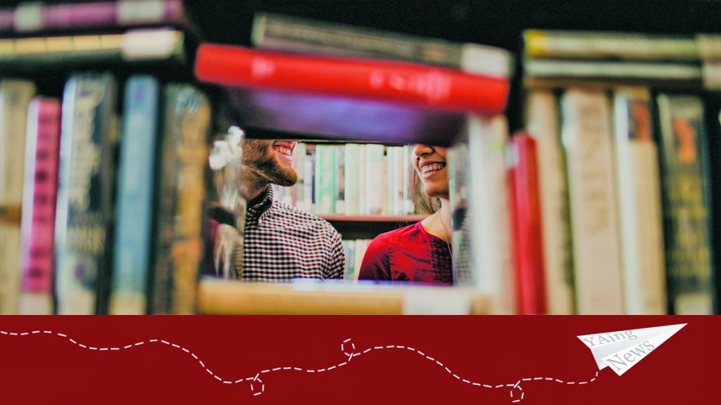 Two people smile, framed by shelved books. The YAing News logo is below the image.